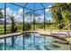 Relaxing in-ground pool area with umbrella and wrought iron fence featuring manicured greenery at 233 Fairway Rd, Rotonda West, FL 33947