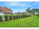 Landscaped backyard with lush lawn, hedges, and community pool view at 1188 Harbor Town Way, Venice, FL 34292