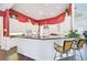 Kitchen with white cabinets, breakfast bar, and red accent wall at 4376 Corso Venetia Blvd, Venice, FL 34293