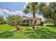Single-story house with screened porch, lush lawn, and palm trees at 1264 Red Oak Ln, Port Charlotte, FL 33948