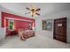 Bright bedroom with red accent wall, ceiling fan, and large window at 4619 Flint Dr, North Port, FL 34286