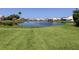 Grass lawn with pond view and neighboring houses at 600 Carriage House Ln # 104, Nokomis, FL 34275