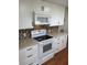 Modern kitchen with white cabinets, updated appliances, and a tile backsplash at 406 Trento, Venice, FL 34285