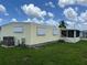 Rear view of a yellow mobile home with AC unit and landscaping at 406 Trento, Venice, FL 34285