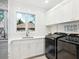 Bright laundry room with white cabinets and new appliances at 1040 Gulf Winds Way, Nokomis, FL 34275