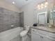 Clean bathroom with granite countertop, bathtub, and grey tile at 10079 Crooked Creek Dr, Venice, FL 34293
