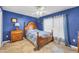 Blue bedroom with a ceiling fan, a window with white curtains, and a wood-look floor at 2091 Marlin Way, Englewood, FL 34224