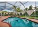 A screened-in pool with a dolphin mosaic, surrounded by lush landscaping and framed by elegant white curtains at 2091 Marlin Way, Englewood, FL 34224