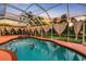 A serene screened-in pool area with a dolphin mosaic, illuminated by a picturesque sunset at 2091 Marlin Way, Englewood, FL 34224