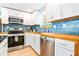Bright kitchen with white cabinets, blue tile backsplash, and stainless steel appliances at 4090 Pelican Shores Cir, Englewood, FL 34223