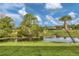 Scenic backyard with lush greenery, a serene pond, and tropical palm trees at 2197 Nita Ter, North Port, FL 34286