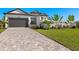 Modern home with dark garage door, paver driveway, and landscaping at 15060 Aquarius Cir, Port Charlotte, FL 33981
