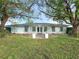 White single-story house with light blue accents, landscaped lawn, and mature trees at 2961 Valencia Rd, Venice, FL 34293