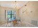 Bright dining area with glass table and chairs, chandelier, and view to backyard at 338 Pembroke Dr # 208, Venice, FL 34293