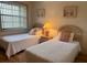 Guest bedroom with twin beds, nightstand and window at 929 Capri Isles Blvd # 22, Venice, FL 34292