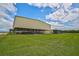 Large metal barn with covered stalls; green lawn at 27000 Harrison Rd, Sidell, FL 34266