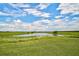 Serene pond surrounded by lush greenery and open fields at 27000 Harrison Rd, Sidell, FL 34266
