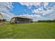 Tan metal barn with screened patio; lush green field at 27000 Harrison Rd, Sidell, FL 34266