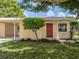 Quaint single-story home with red door, landscaping and large tree at 1020 Roberta St, Venice, FL 34285