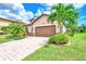 Single-story home with brown garage door, landscaping, and brick paver driveway at 12261 Canavese Ln, Venice, FL 34293