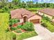 Single-story house with terracotta roof, lush landscaping, and a brick paver driveway at 12261 Canavese Ln, Venice, FL 34293