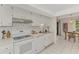 White kitchen featuring modern backsplash, tile floors, and bright lighting at 5103 Greencroft Rd, Sarasota, FL 34235