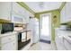 Galley kitchen with white cabinets, black stove, and door to outside at 475 Circlewood Dr # O18, Venice, FL 34293