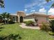 Tan house with lush landscaping, a two-car garage, and walkway at 117 Savona Way, North Venice, FL 34275