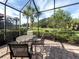 Relaxing screened patio features brick pavers, a table with chairs, and views of the peaceful backyard at 277 Mestre Pl, North Venice, FL 34275