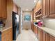 Kitchen with wood cabinets, black appliances, and a view to the living area at 760 Village Cir # 212, Venice, FL 34292