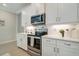 Modern kitchen with white cabinets, quartz countertops, and stainless steel appliances at 240 Teramo Way, Nokomis, FL 34275