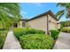 Side view of a tan house with a two-car garage and neatly trimmed hedges at 1780 Batello Dr, Venice, FL 34292