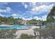 Community pool surrounded by tables, chairs, lounge chairs, and tropical foliage at 217 Carriage House Ln # 217, Nokomis, FL 34275