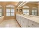 Bright bathroom featuring a double vanity with white cabinets and a large mirror, complemented by natural light at 594 Sawgrass Bridge Rd, Venice, FL 34292
