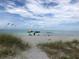 Beach view with colorful umbrellas, inviting chairs on the sandy shore, and boats sailing on the horizon at 594 Sawgrass Bridge Rd, Venice, FL 34292