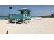 Beachside lifeguard tower with a vibrant green flag, overseeing sunbathers and swimmers on the sandy beach at 594 Sawgrass Bridge Rd, Venice, FL 34292