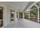 Screened porch with concrete flooring, glass door, and views of tropical landscaping at 1311 Tuscany Blvd, Venice, FL 34292