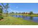 Scenic view of a lake with lush green grass and mature trees at 10780 Tarflower Dr # 102, Venice, FL 34293