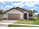 Single-story home with tan garage door and red tile roof at 24273 Spartina Dr, Venice, FL 34293