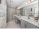 Bright bathroom featuring double vanity with gray cabinets, a glass enclosed shower, and neutral toned tile at 12586 Oak Hill Way, Parrish, FL 34219