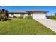 Single-story house with a white garage door and landscaped lawn at 12026 Corsica Ln, North Port, FL 34287