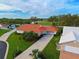 Aerial view of single-story home with tile roof, driveway, and green lawn, near golf course at 1618 Slate Ct, Venice, FL 34292