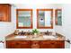 Bathroom boasts double sinks with granite countertops, complemented by framed mirrors and wood cabinetry at 172 Southampton Pl # 346, Venice, FL 34293