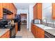 Functional kitchen features wooden cabinets, granite countertops, tile backsplash, and black appliances at 172 Southampton Pl # 346, Venice, FL 34293