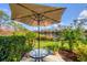 Relaxing outdoor patio with a table, umbrella, and serene view of the lush landscape and pond at 804 Montrose Dr # 103, Venice, FL 34293