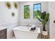 Elegant white bathroom with a soaking tub, decorative wall art, and green leafy plants at 1109 Bayshore Rd, Nokomis, FL 34275