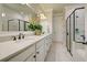 Elegant bathroom boasting dual vanities, a large mirror, and a walk-in shower at 13848 Rinuccio St, Venice, FL 34293