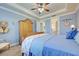 Bright bedroom with light blue walls and bedding, featuring a wooden armoire and ceiling fan at 13848 Rinuccio St, Venice, FL 34293