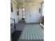 Charming covered front porch featuring a striped rug, white storage door, and view of screen door at 6234 Parakeet Rd, Englewood, FL 34224