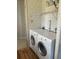 Bright laundry area featuring a front-load washer and dryer with overhead shelving for efficient storage solutions at 6234 Parakeet Rd, Englewood, FL 34224